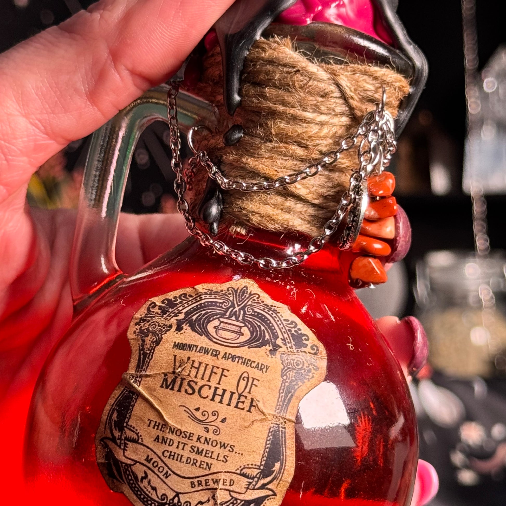 Bottle labeled 'Whiff of Mischief' held by a hand with a blurred background